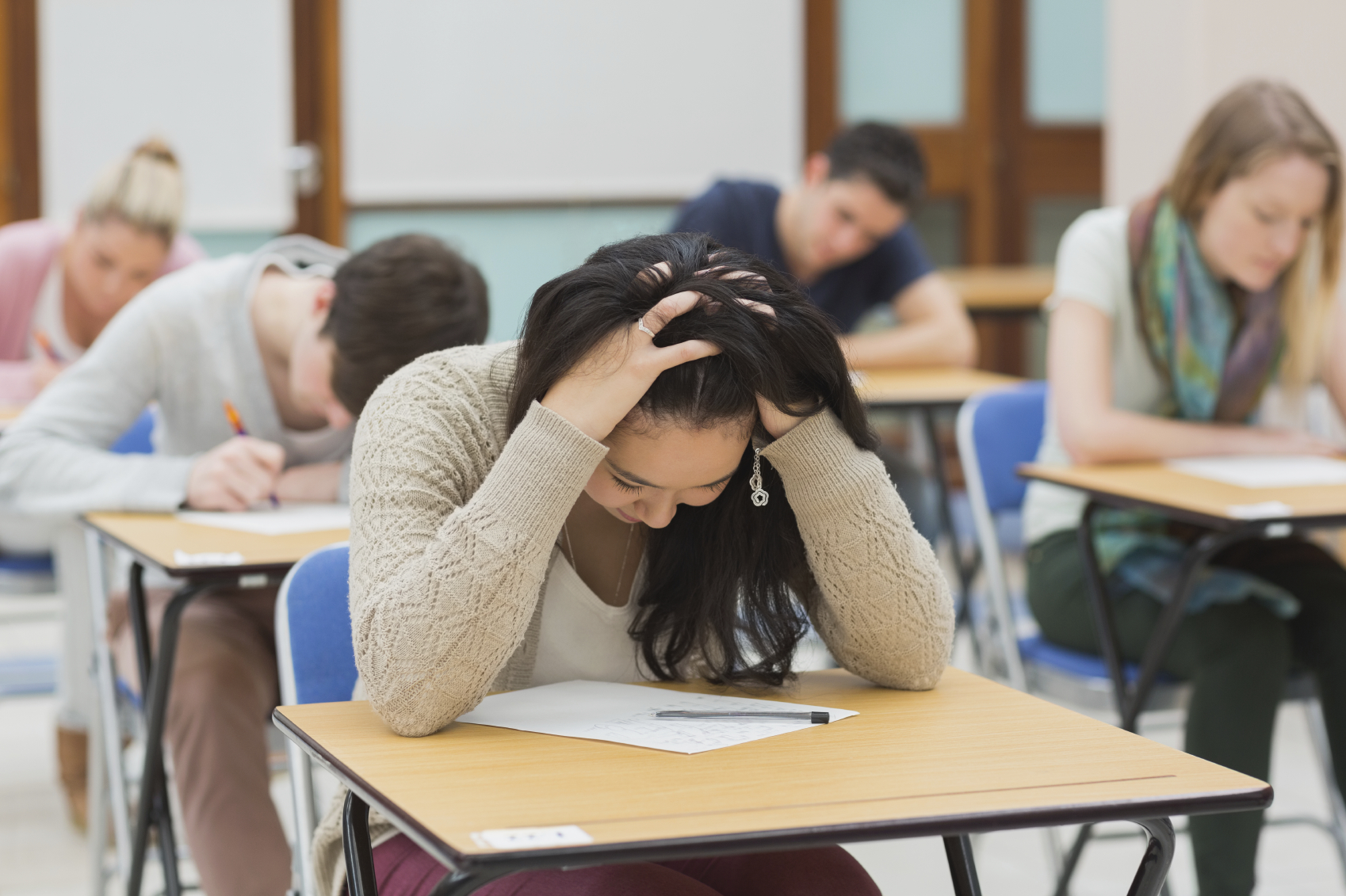 Stressed student sitting in a classroom at a table while doing a test