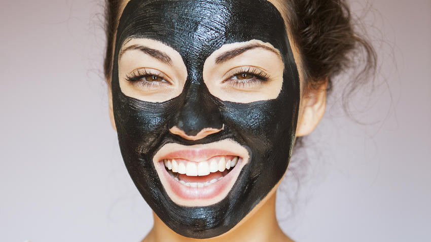 Young woman with face mask of therapeutic black mud